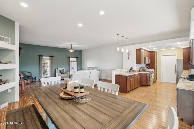 dining space with light hardwood / wood-style flooring, built in shelves, and ceiling fan