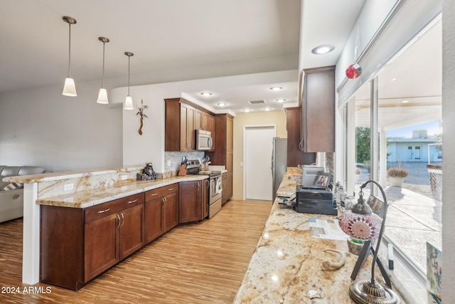 kitchen with tasteful backsplash, appliances with stainless steel finishes, kitchen peninsula, light hardwood / wood-style floors, and decorative light fixtures