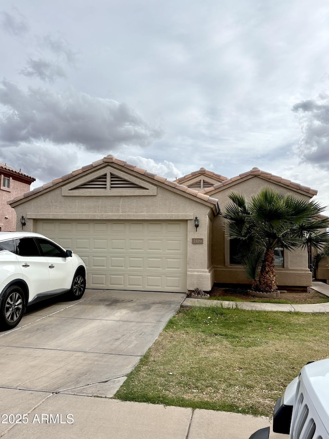 view of front facade with a tiled roof, driveway, an attached garage, a front yard, and stucco siding