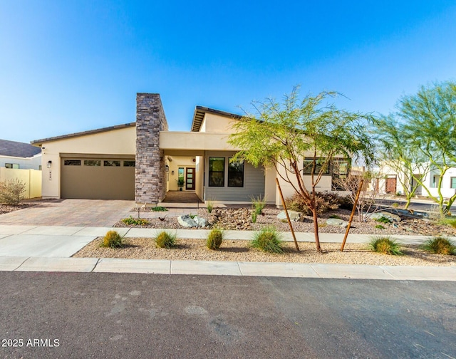 view of front of property with decorative driveway, an attached garage, and stucco siding