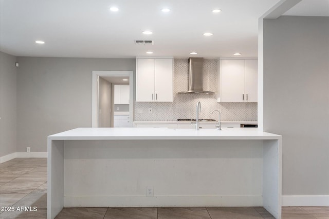 kitchen featuring tasteful backsplash, white cabinets, wall chimney exhaust hood, and gas cooktop