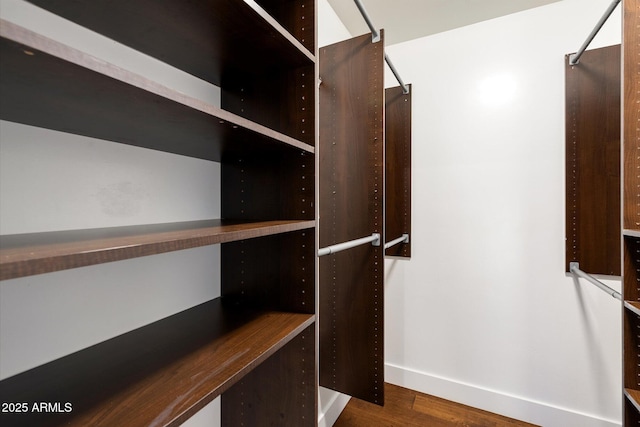 spacious closet featuring dark hardwood / wood-style floors and built in desk