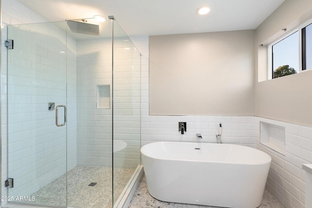 bathroom featuring tile walls and separate shower and tub