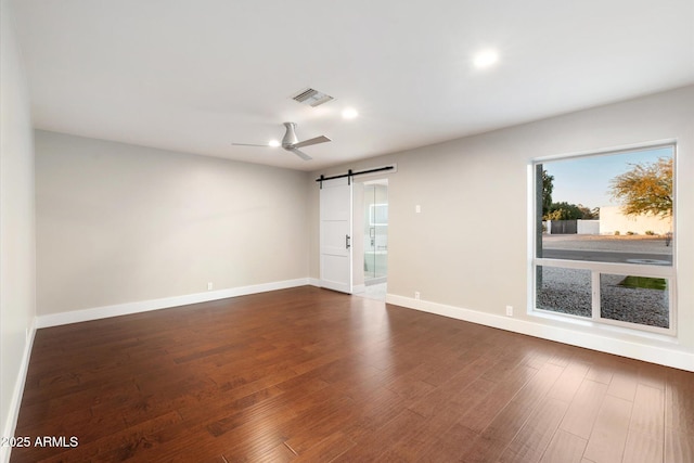 unfurnished room featuring dark hardwood / wood-style floors and a barn door