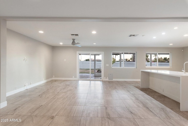 unfurnished living room with ceiling fan and a wealth of natural light