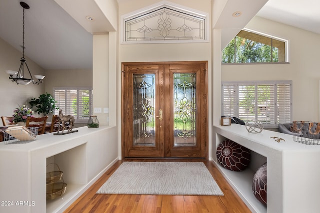 entryway with a healthy amount of sunlight, high vaulted ceiling, and hardwood / wood-style flooring