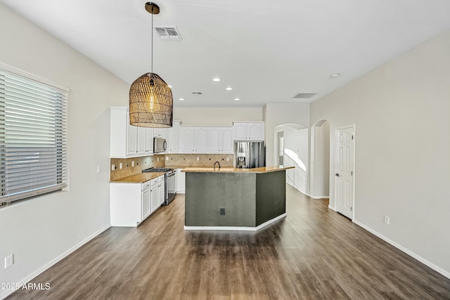 kitchen featuring arched walkways, white cabinetry, visible vents, appliances with stainless steel finishes, and decorative backsplash