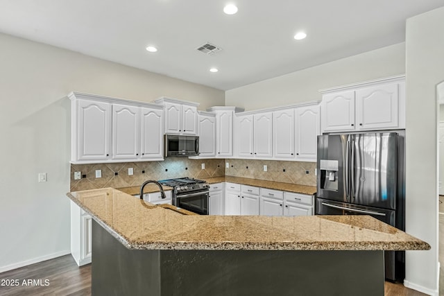 kitchen with tasteful backsplash, visible vents, dark wood-type flooring, stainless steel appliances, and white cabinetry