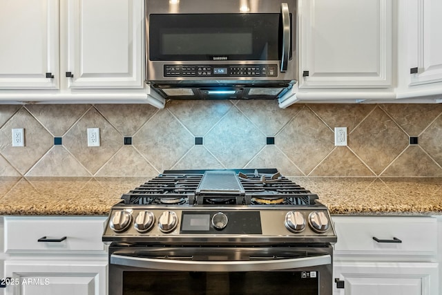 kitchen featuring appliances with stainless steel finishes, white cabinets, decorative backsplash, and light stone countertops