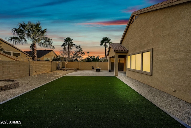 yard at dusk featuring a fenced backyard and a patio