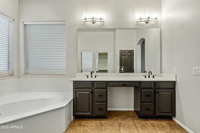 full bath featuring a bath, double vanity, a sink, and tile patterned floors