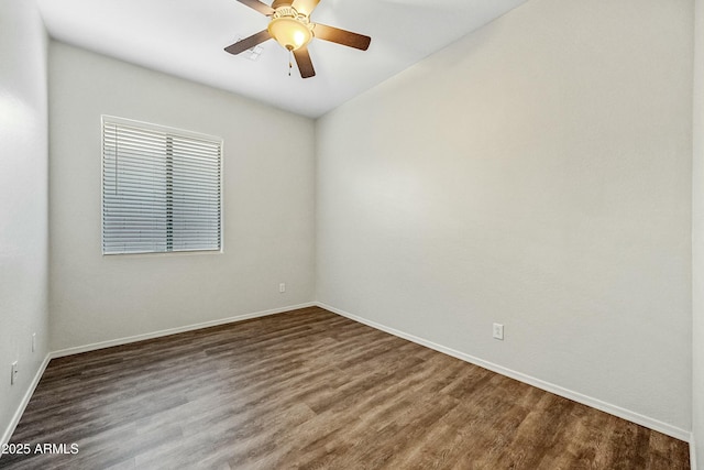 spare room with dark wood-style floors, baseboards, and a ceiling fan