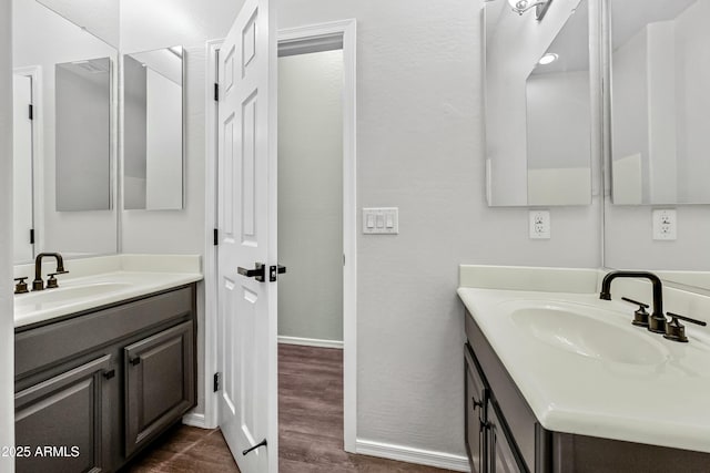 bathroom with two vanities, a sink, and wood finished floors