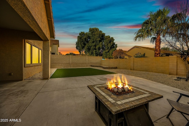 patio terrace at dusk with an outdoor fire pit and a fenced backyard