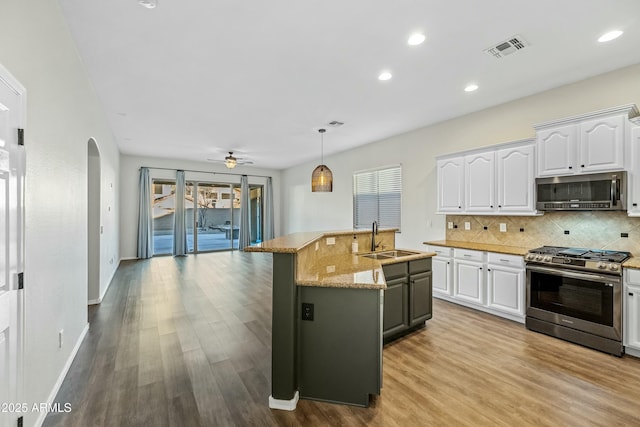 kitchen featuring visible vents, white cabinets, decorative backsplash, stainless steel appliances, and a sink