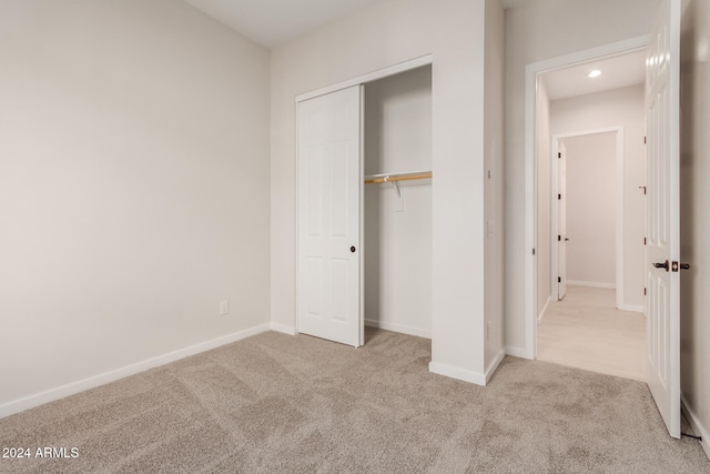 unfurnished bedroom with light carpet and a closet