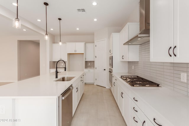 kitchen featuring wall chimney exhaust hood, sink, an island with sink, and stainless steel appliances