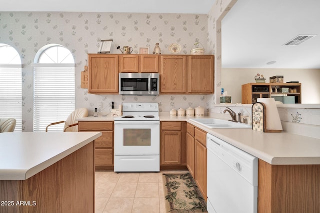 kitchen with white appliances, kitchen peninsula, sink, and light tile patterned floors