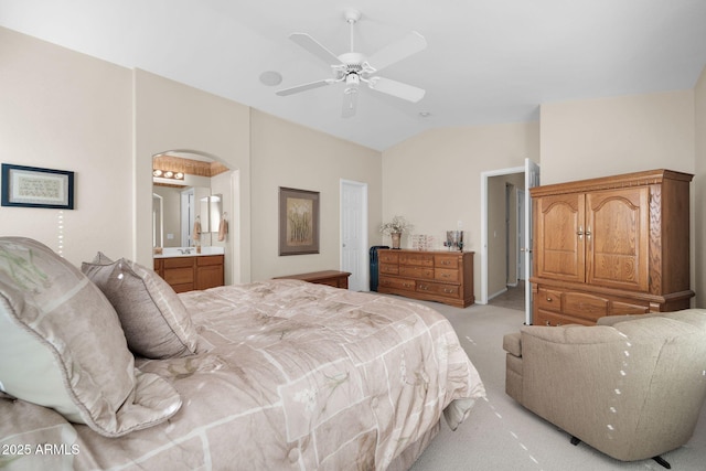 carpeted bedroom with connected bathroom, vaulted ceiling, and ceiling fan