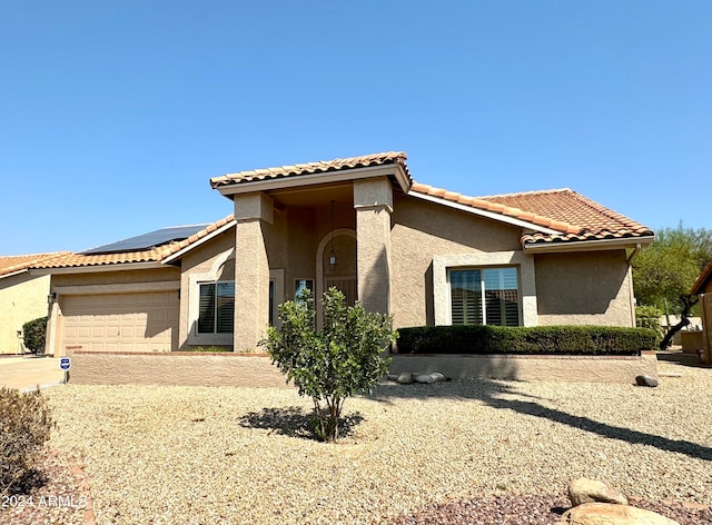 mediterranean / spanish-style home featuring a garage and solar panels