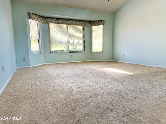 carpeted empty room with lofted ceiling