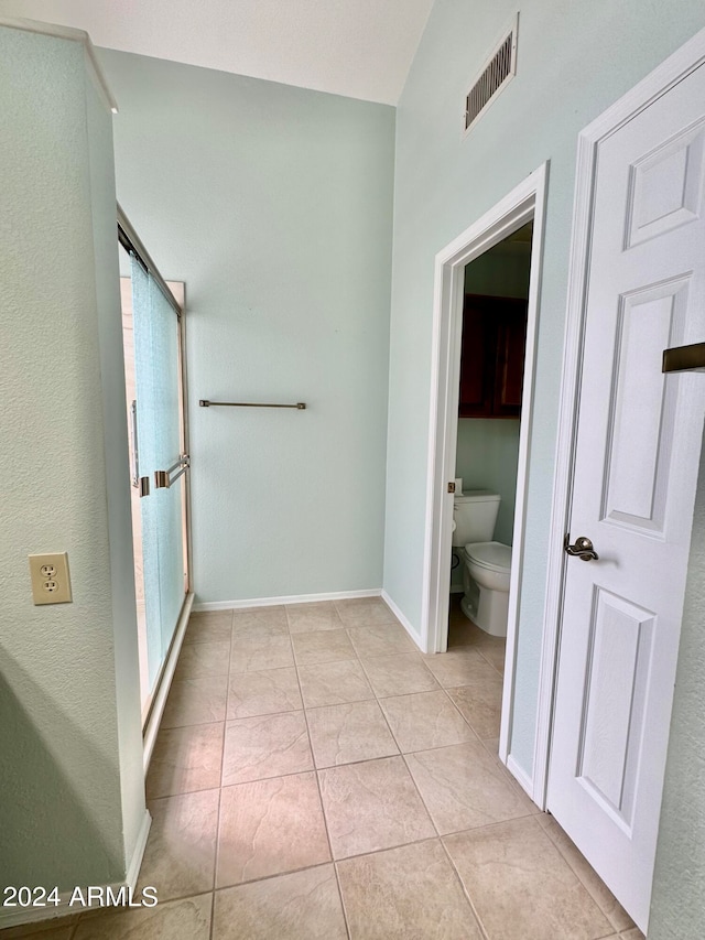 bathroom with walk in shower, toilet, and tile patterned floors