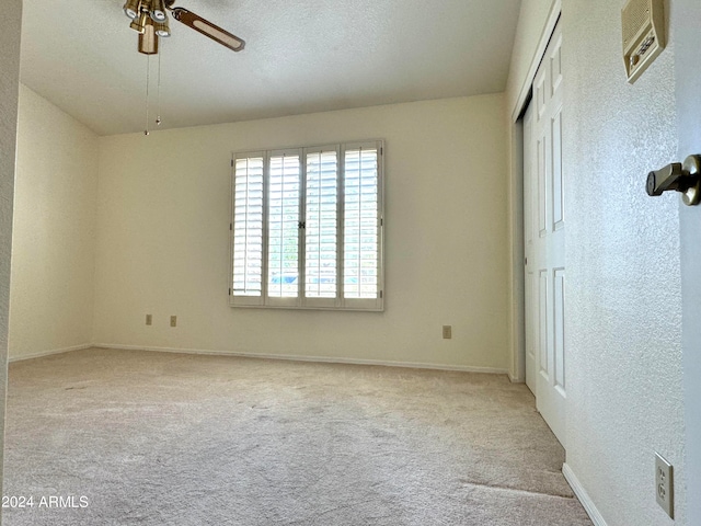 empty room with a textured ceiling, ceiling fan, and light colored carpet