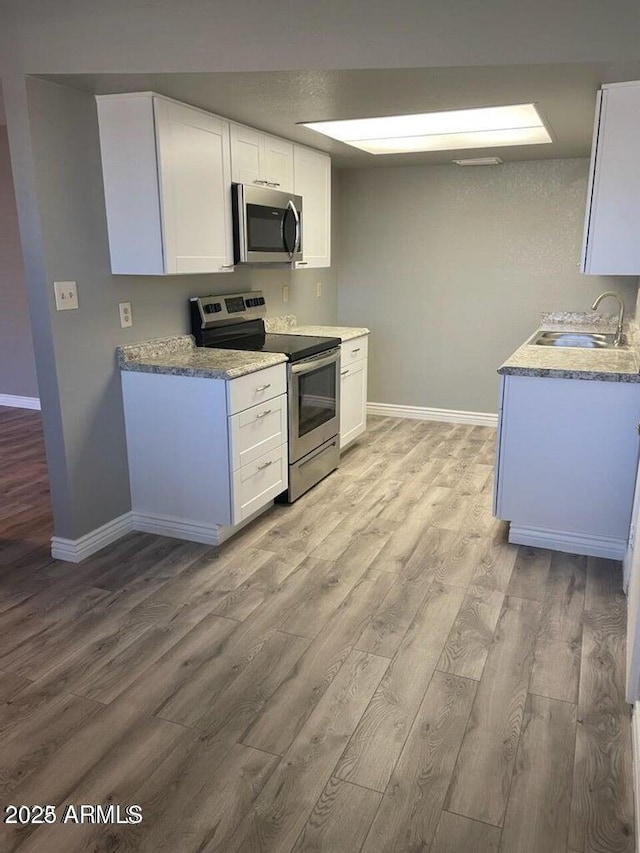 kitchen featuring appliances with stainless steel finishes, light hardwood / wood-style floors, sink, and white cabinets