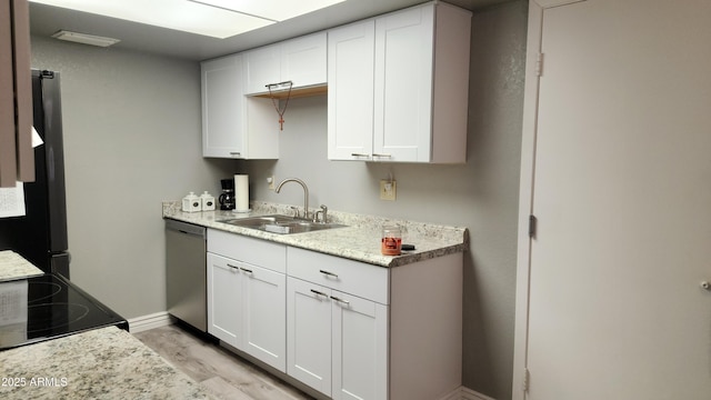 kitchen with sink, appliances with stainless steel finishes, light stone countertops, white cabinets, and light wood-type flooring