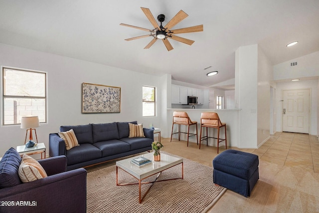 tiled living room featuring ceiling fan and vaulted ceiling