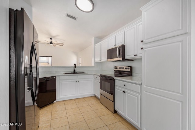 kitchen with light tile patterned flooring, lofted ceiling, sink, black appliances, and white cabinets