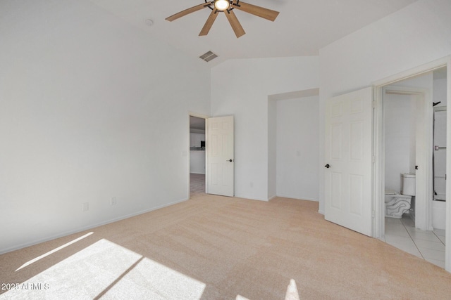 unfurnished bedroom with light colored carpet, high vaulted ceiling, ensuite bath, and a walk in closet