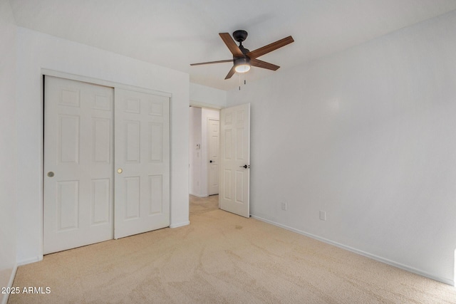 unfurnished bedroom featuring ceiling fan, light colored carpet, and a closet