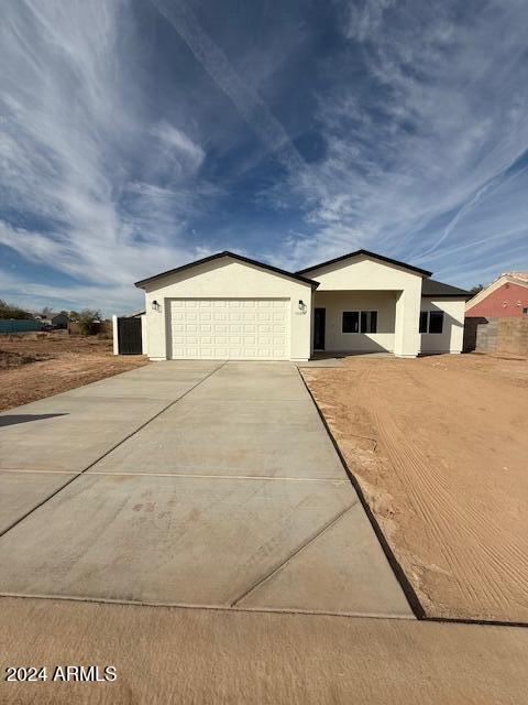 ranch-style home featuring a garage, concrete driveway, and stucco siding