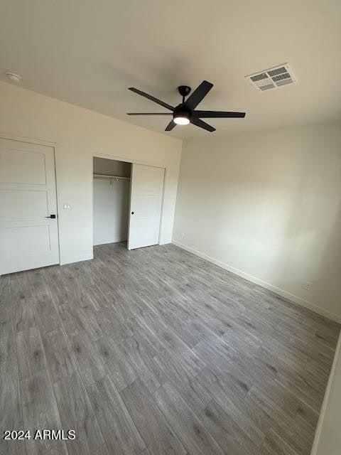 unfurnished bedroom with hardwood / wood-style floors, ceiling fan, and a closet