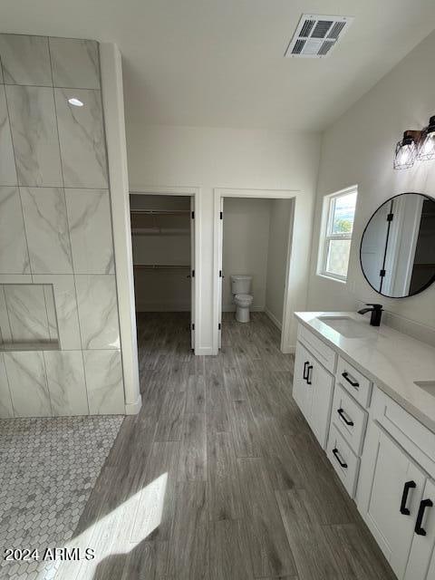 bathroom with wood-type flooring, vanity, toilet, and walk in shower