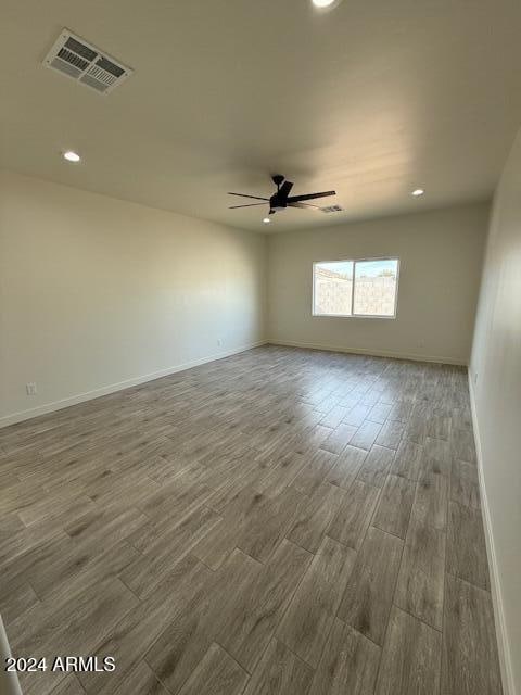 empty room with baseboards, wood finished floors, visible vents, and ceiling fan