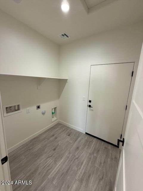 laundry area featuring electric dryer hookup, visible vents, washer hookup, wood finished floors, and laundry area