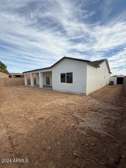 back of house featuring stucco siding, central AC unit, and fence