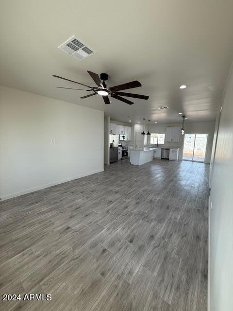 unfurnished living room with ceiling fan and wood-type flooring