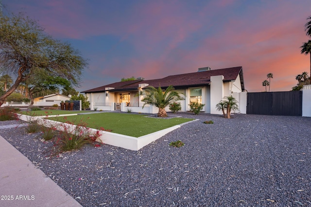 view of front of property with fence, stucco siding, and a yard