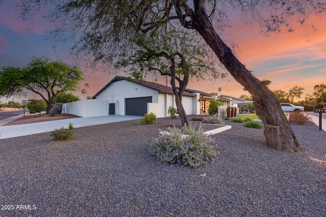 single story home featuring concrete driveway, fence, and a garage