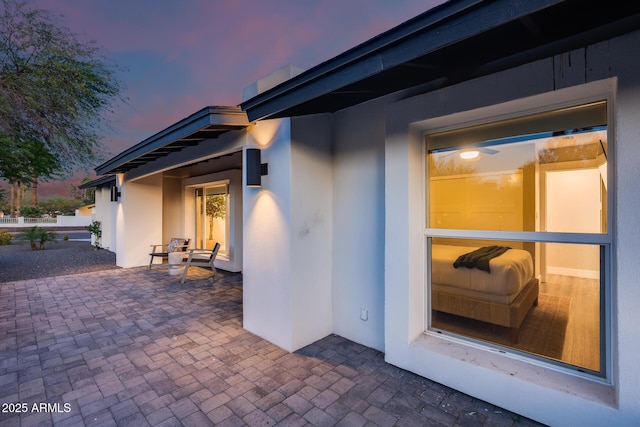 exterior entry at dusk with a patio area and stucco siding