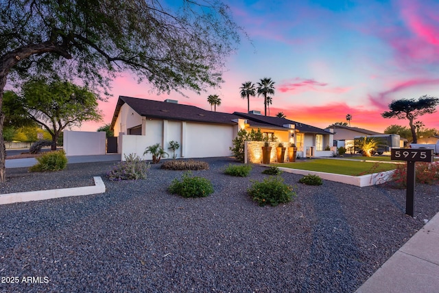 ranch-style house featuring a garage, fence, and stucco siding
