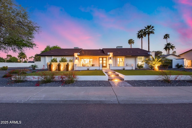 ranch-style house featuring fence, a front lawn, and stucco siding