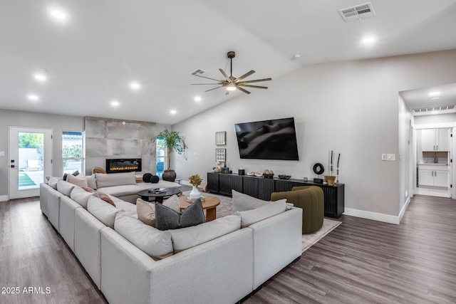living area featuring visible vents, baseboards, wood finished floors, and vaulted ceiling