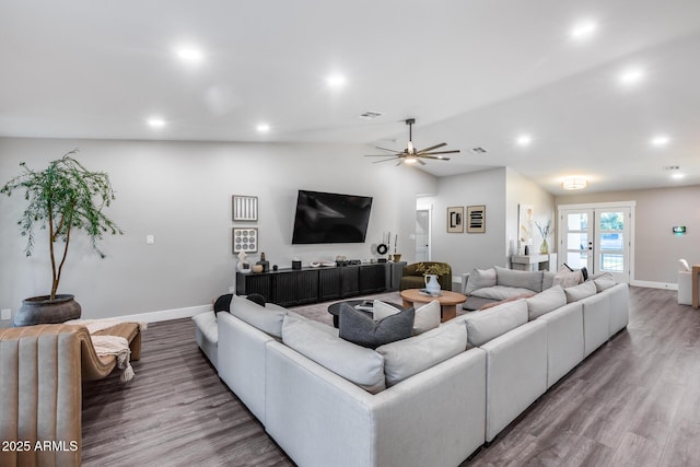 living room with baseboards, a ceiling fan, vaulted ceiling, and wood finished floors