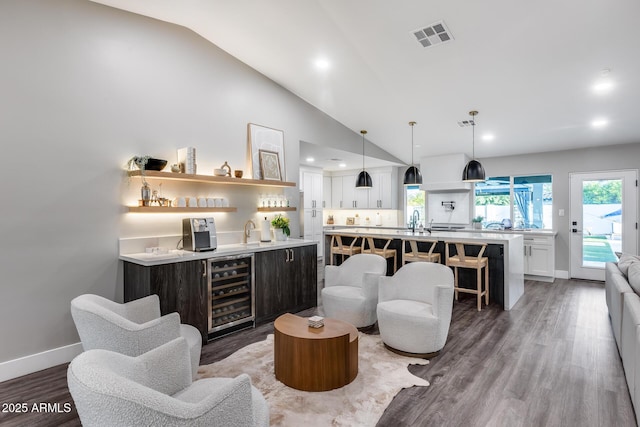 bar featuring indoor wet bar, wood finished floors, vaulted ceiling, wine cooler, and visible vents