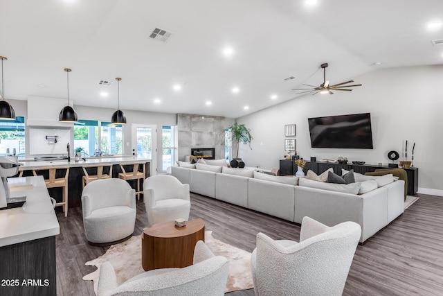living area featuring visible vents, a ceiling fan, lofted ceiling, and wood finished floors