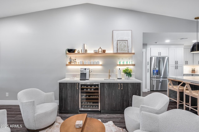 bar featuring wine cooler, lofted ceiling, indoor wet bar, stainless steel refrigerator with ice dispenser, and dark wood-type flooring
